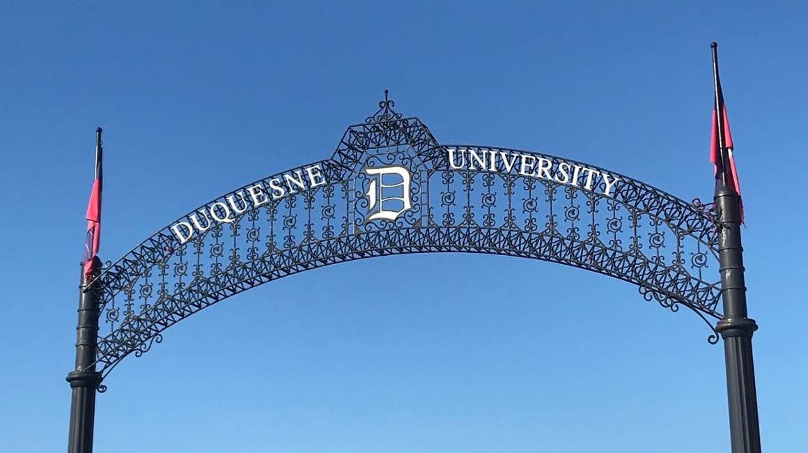 An arch that says Duquesne University. Behind it is a blue sky.