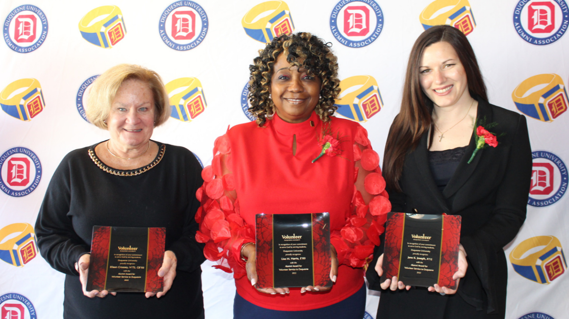 Three people standing together holding awards