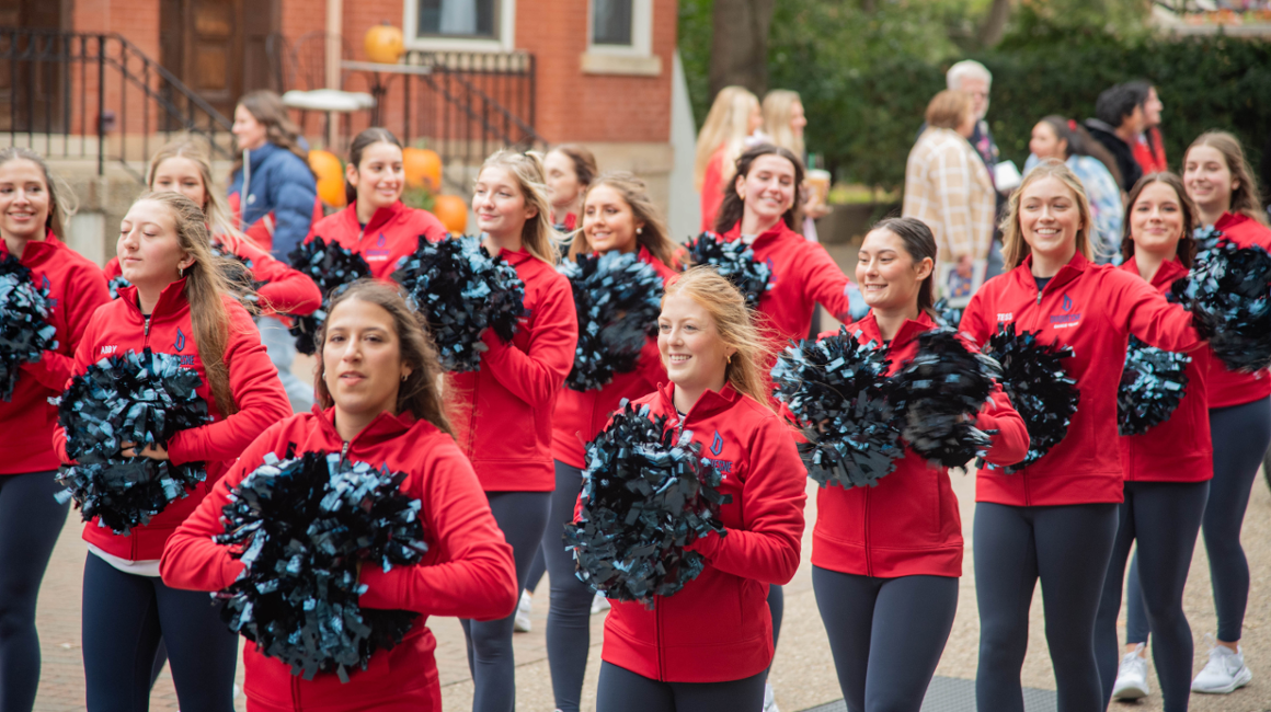 Cheerleaders walking in a parade holding pom poms