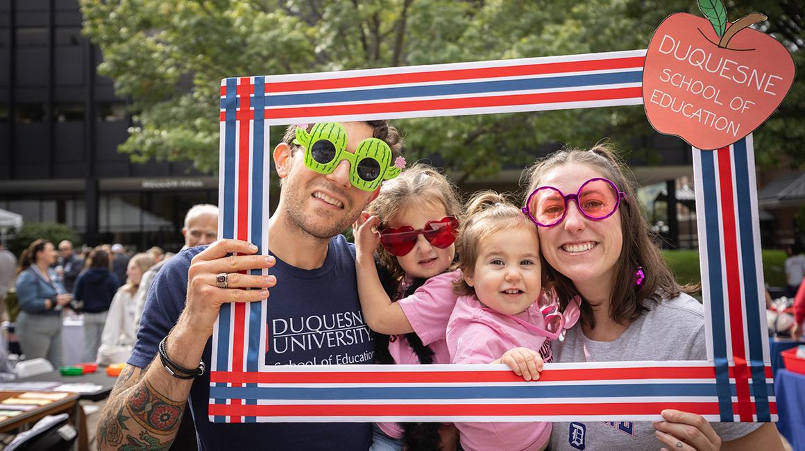 Family posing inside a picture frame at Homecoming