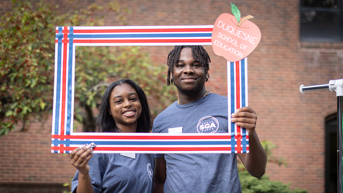 Two students posing within a picture frame