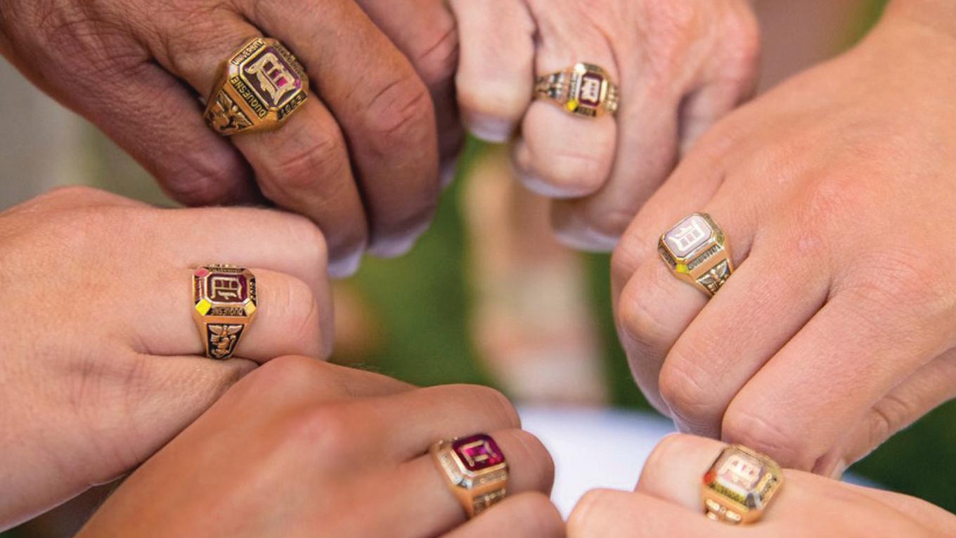 hands wearing Duquesne class rings in a circle