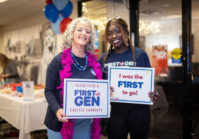Dr. Leanna Fenneberg and a Duquesne student hold up signs that say 