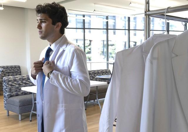 DUQCOM DO student preparing for the big ceremony with his white coat!