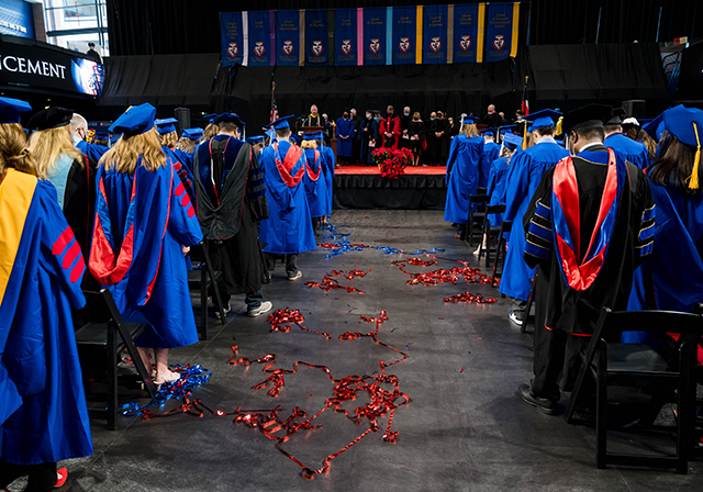 Graduates in caps at commencement ceremony looking at stage.