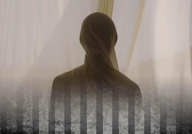 Shrouded person behind bars.