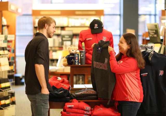 Man and a woman showing off DU branded clothes