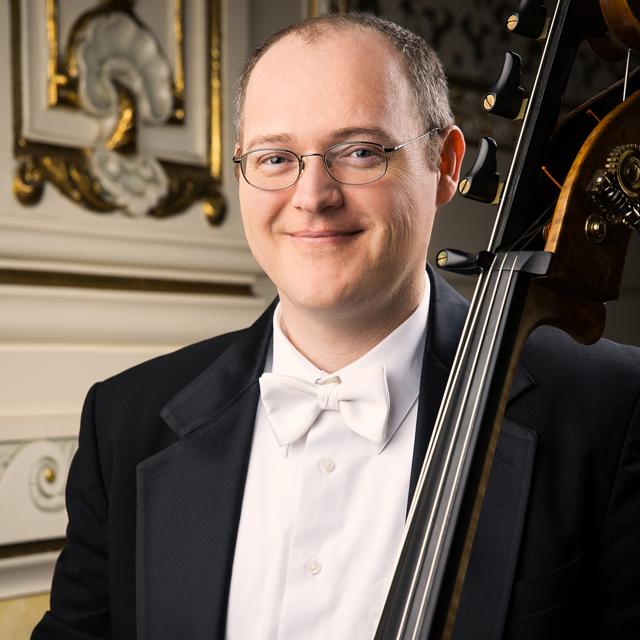 Man poses with a double bass.