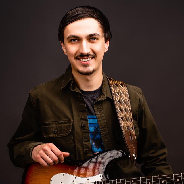 Alex Price holds a guitar.