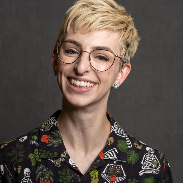 Amelia Van Howe poses for a headshot in front of a gray background.