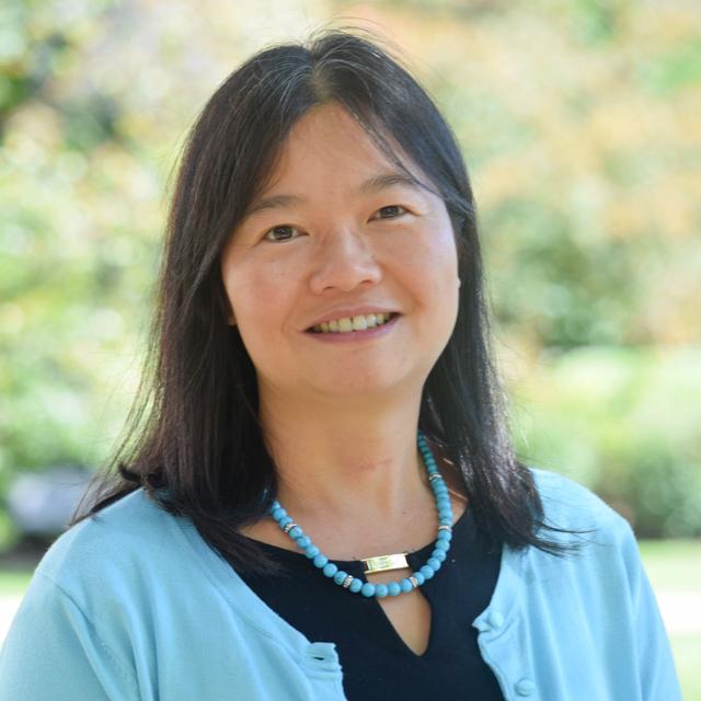 Dr. Ann Huang's headshot with campus trees in the background