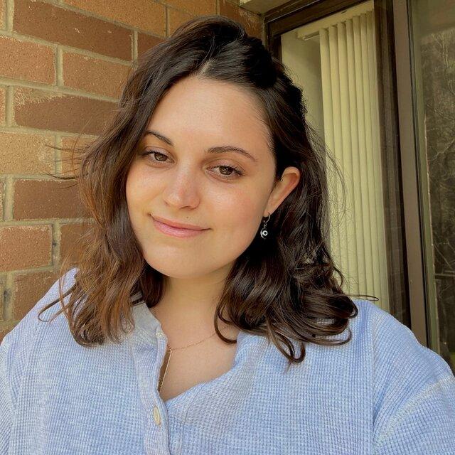 Brooke smiles in a light blue sweater.