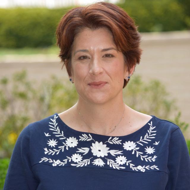 Headshot of Dr. Carla Meyer with trees and campus wall in background