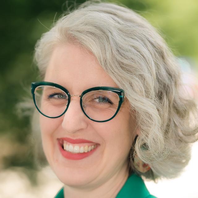 smiling woman in green shirt and green glasses