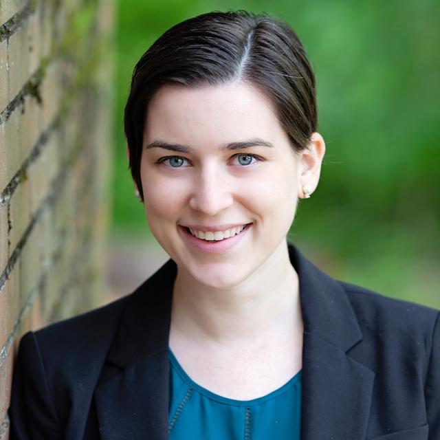 Carrie McCormack poses for a headshot against a brick wall outdoors