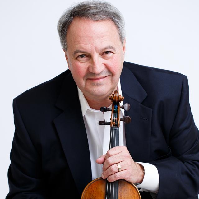 Charles Stegeman holds a violin for a headshot against a light gray background.