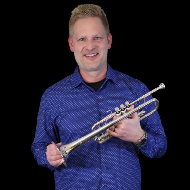 man in blue shirt holds trumpet in front of black background