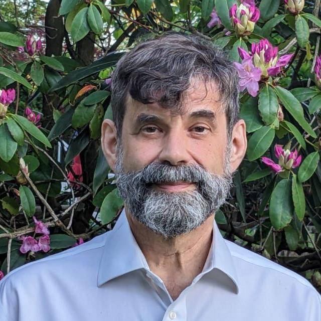 Headshot of Dr. Daniel Burston in front of outdoor florals