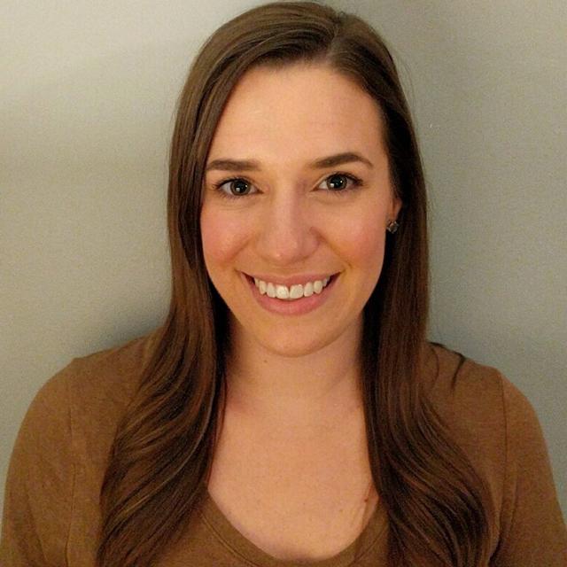 Deanna Diederich poses for a headshot against a beige background.