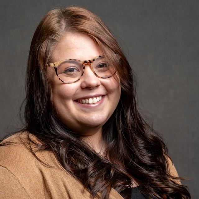 Emma Pearson poses for a headshot against a gray background.