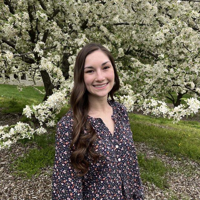 Erica smiles in front of a blooming tree.