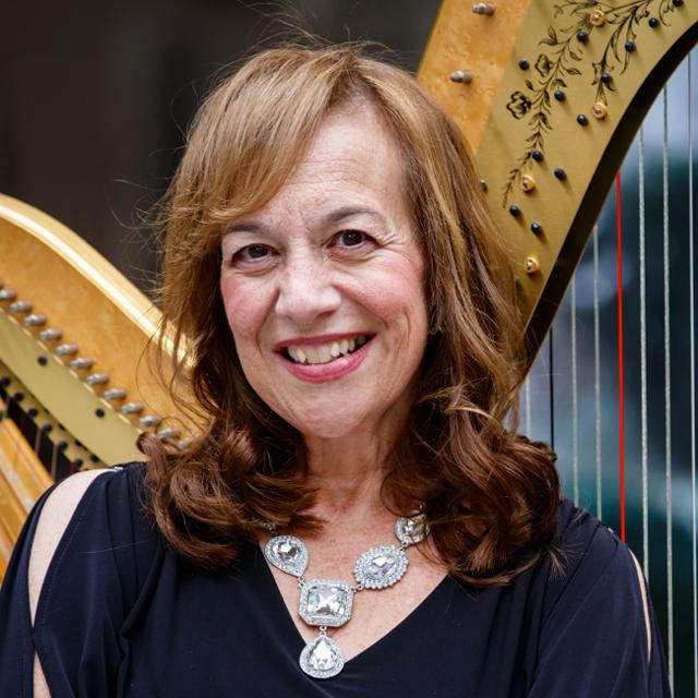 Gretchen Van Hoesen poses in front of a harp.