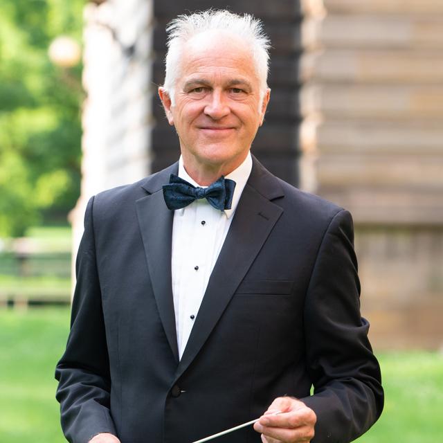 Dr. James Gourlay poses for an outdoor photo holding a baton.