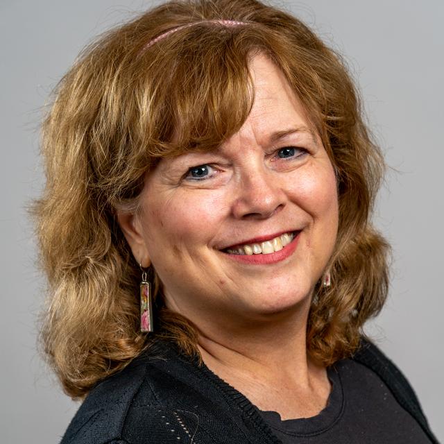 Jayne McDonald poses for a headshot in front of a gray background.