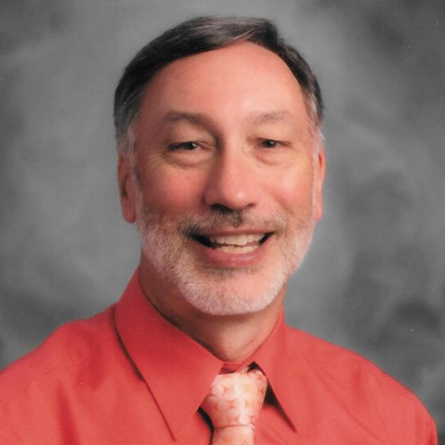 Jeffrey Leonhardt poses for a headshot in front of a gray background.