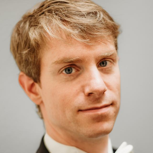 Jim Benoit poses for a head shot in front of a beige background.