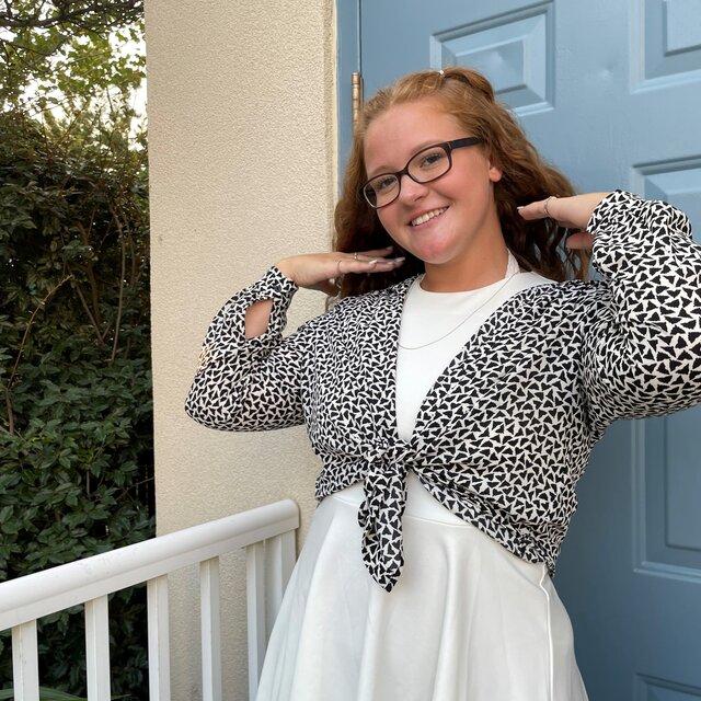 Johnna poses in a gray sweater and white dress.