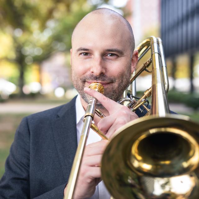 Sebastian Vera holds a trombone outdoors.