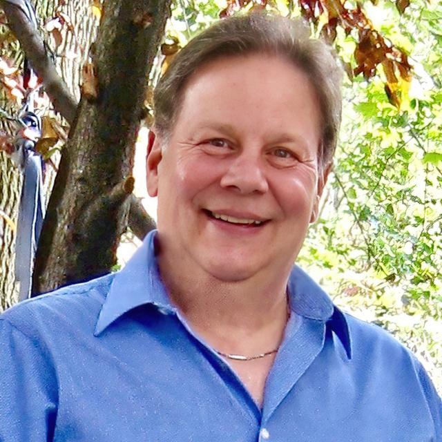 John Soroka poses for a headshot in front of a tree.