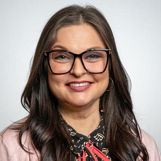 Person with long brown hair smiling in front of a grey background