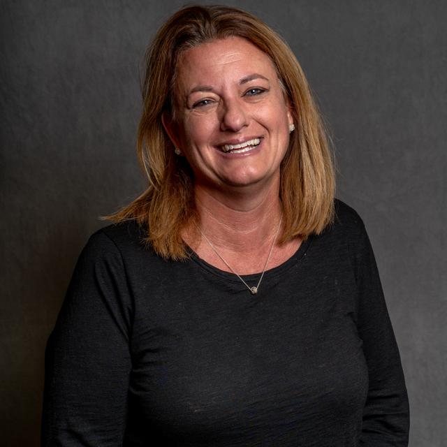 Karyn Reinhart poses for a headshot against a gray background.