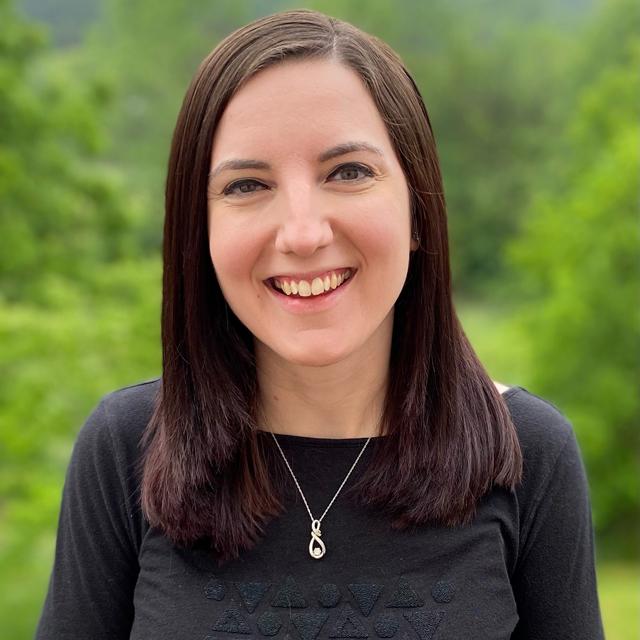 Kayla Kurtz poses for a headshot against a blurry outdoor background.