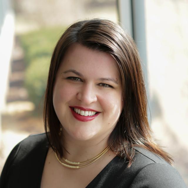 Laura Reynolds poses for a headshot in front of a blurry background.