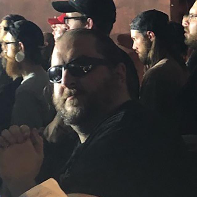 Luke Boegel wears sunglasses in a crowd of people.