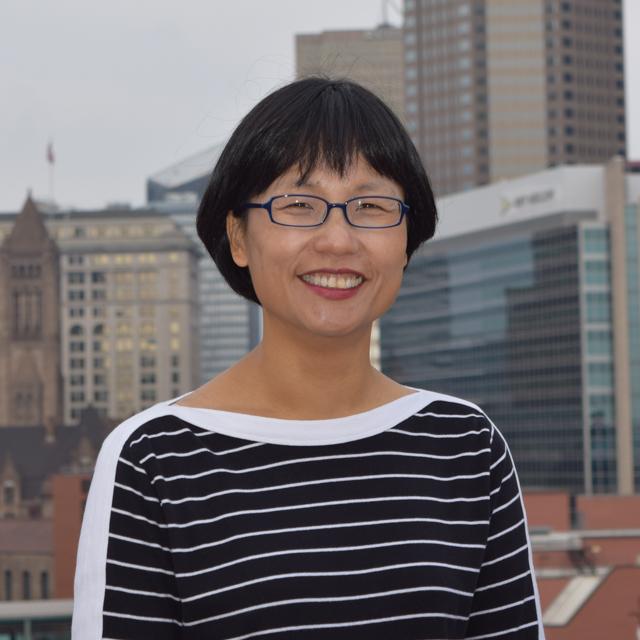 Headshot of Dr. Misook Heo with Pittsburgh cityscape from Duquesne's campus in the background