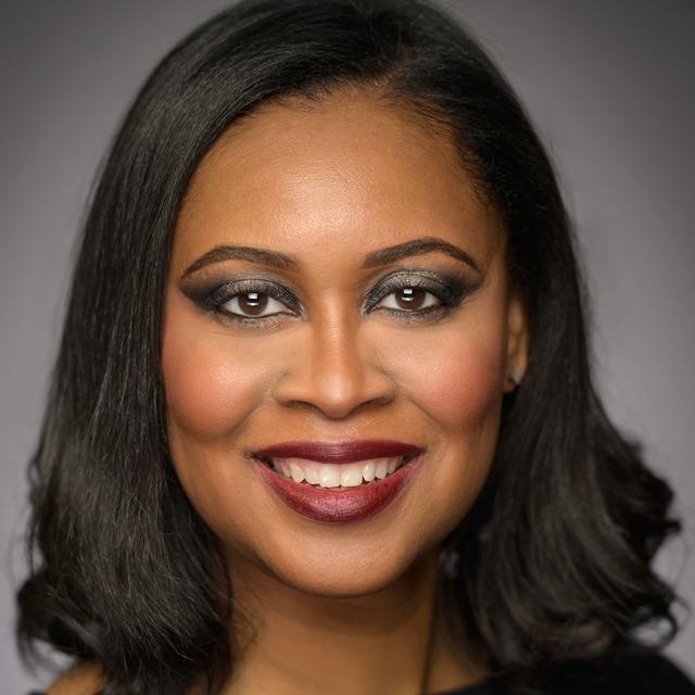 Nicole Jenkins poses for a headshot in front of gray background.