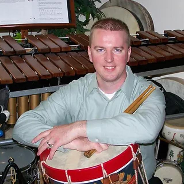 P.J. Gatch poses in front of an assortment of percussion instruments.