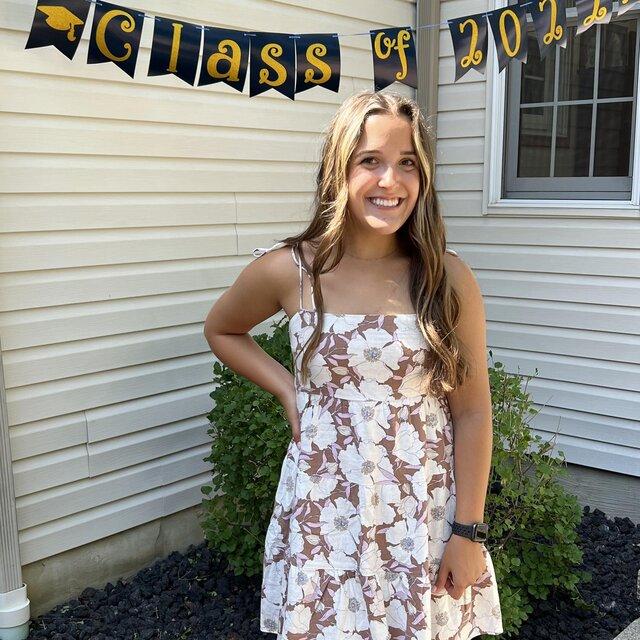 Rachel poses for a photo in front of a "Class of 2022" banner.