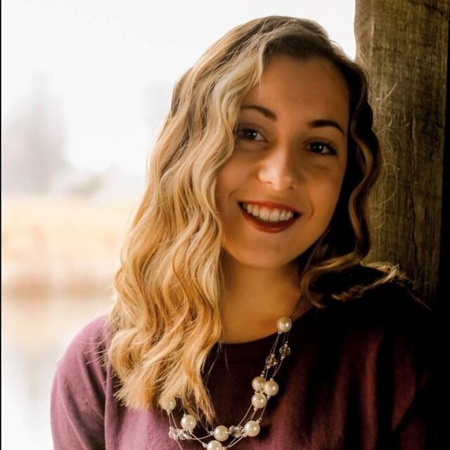 Rachel smiles for a portrait photo in a purple sweater