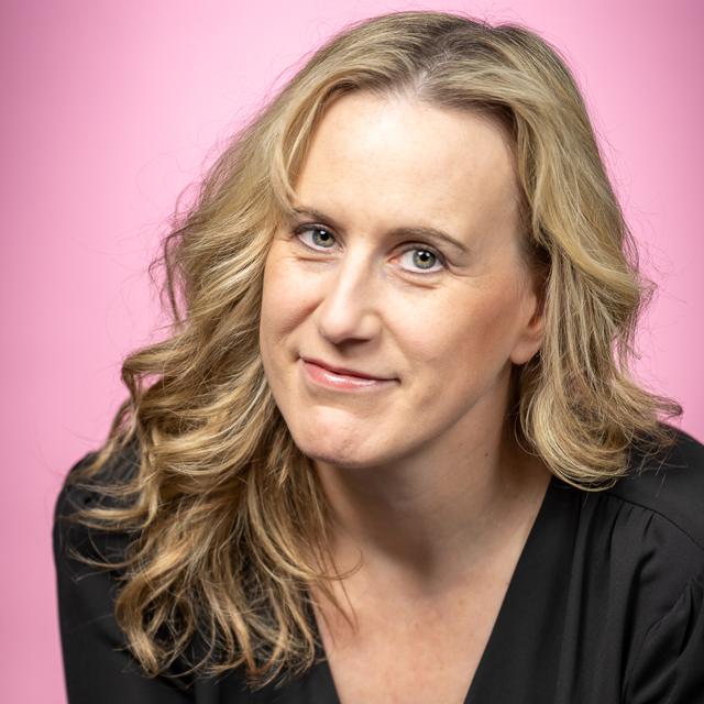 Rachel Whitcomb poses for a headshot in front of a black background.