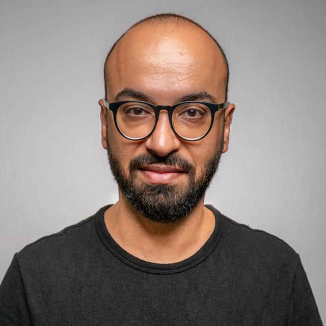person in black t-shirt with black glasses posing for a photo