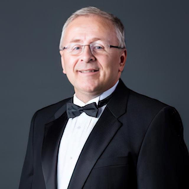 Shawn Funk wears a tuxedo in front of a gray background.