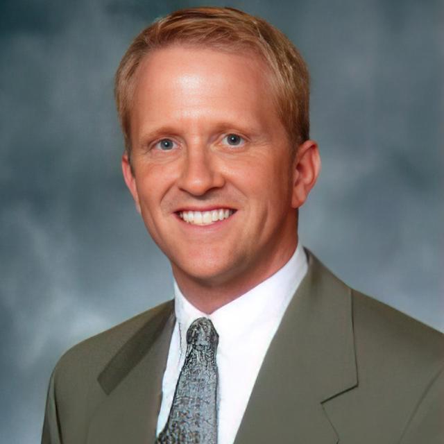 Todd Kuczawa poses for a photo in front of a blue background.