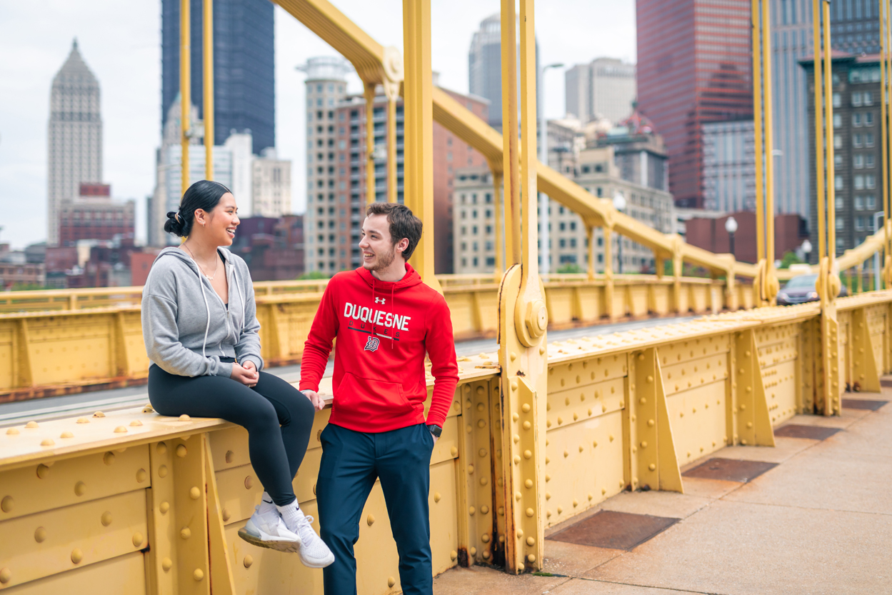 female and male student in Duquesne gear on Rachel Carson Bridge Pittsburgh