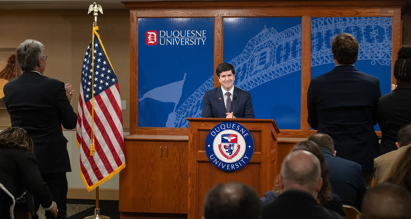 David Dausey standing at a podium addressing campus colleagues.