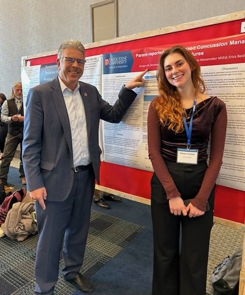 President Gormley standing with a female student in front of her poster presentation.